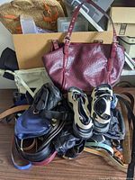 Lot including large maroon ostrich-textured leather tote purse, black handbag, multiple casual shoes in white, black, and blue tones piled together