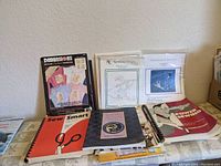Photo of embroidery transfer kit and several spiral-bound sewing instruction books on table.