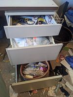 Top two drawers open filled with assorted sewing tools and notions