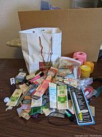 Photo showing white retail bag filled with assorted sewing notions including zippers, buttons, ribbons, and yarn skeins in various colors