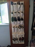 Multiple pairs of shoes organized in white hanging shoe organizer.