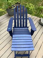 Front view of blue Trex style Adirondack chair with footrest showing slatted seat, armrests and backrest on outdoor deck.
