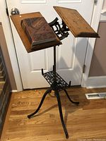 Front view of the antique dual wooden book stand on ornate cast iron base, showing one book placed on the left rest.
