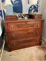 Front view of antique wooden dresser showing three large drawers and two smaller drawers on top, with metal handles and scratches visible on surface.