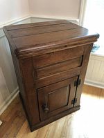 Antique wooden ice box cabinet showing exterior front with door and top lid closed.