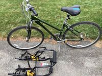 Full side profile photo showing green Jamis Citizen bike with deflated tires and black bike rack placed on ground