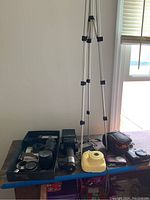 Wide view of all items laid out on a table, showing multiple cameras, lenses, a tripod and case.