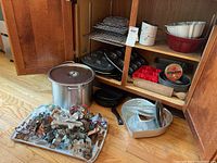 Overview of bakeware set inside cabinet and cookie cutters on tray outside cabinet.