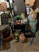Wide view showing 34-inch Mrs. Bunny blow mold figure with assorted Easter decorations including baskets, eggs, chicks, and cookie cutters around it on the floor.