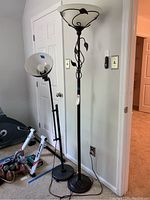 Two metal floor lamps side by side against a wall showing overall height and design.