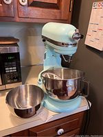 Tilt-head stand mixer in pastel color with two bowls on counter