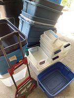 Multiple plastic storage bins stacked with some having matching lids and others missing lids. Coasted by dust and dirt.