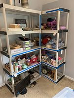 Photo showing two plastic five-shelf shelving units filled with various craft and household items.