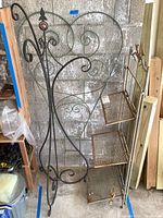 Overall view of metal trellis, tripod stand, and bakers rack in storage area showing wear and rust