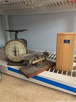 Photo showing Columbia 9 Family Scale and EKC balance scale with weights on a shelf
