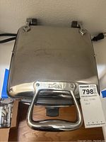 Top view of closed waffle maker showing stainless steel exterior and All-Clad logo