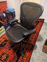 Front-left three-quarter view showing mesh seat, armrests and five-star base with casters