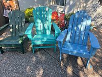 Three chairs in dark green, teal, and light blue shown outdoors on pebbled patio.