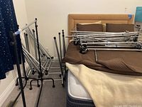 Wide view showing several metal garment racks stacked and disassembled in a room.