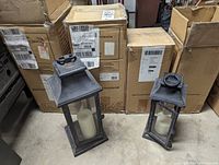 Two metal-framed lanterns in front of cardboard boxes