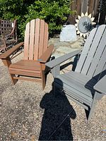 Pair of Adirondack chairs side by side in an outdoor patio setting, showing brown and gray colors