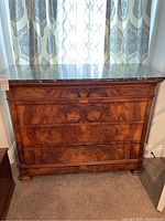 Front view of wooden chest of drawers with dark brown marble top and four drawers