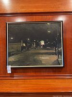 Framed night street scene painting, full front view hanging on wood panel