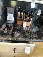 Overview of counter showing two knife blocks, loose knives, steak knives, scissors and mesh tray