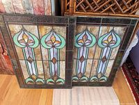 Two identical stained glass panels side by side on hardwood floor
