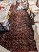Overall view showing the rug laid under a dining table and chairs, highlighting the pattern and border.
