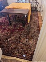 Full view of the rug in a room setting under a table with chairs showing overall condition and pattern.