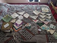 Full view of assortment of handkerchiefs laid out on patterned fabric surface showing various folded and unfolded pieces in different colors and styles.
