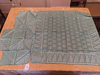 Full view of the two-tone chrysanthemum decorated linen tablecloth alongside four matching napkins placed on top.