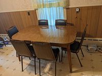 Full view of the rectangular laminate top table with wood grain finish and six chairs around it (chairs not included in lot).