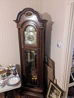 Full view of the wooden grandfather clock showing overall height, single door with glass panel, pendulum, and clock body details.