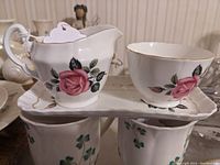 Side view of the Adderley bone china creamer and sugar bowl on the matching tray showcasing the pink rose design and gold-trimmed scalloped edges.