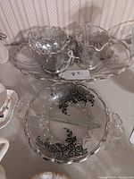 Four mid-century glass pieces with silver floral overlay on a tray, showing decorative scalloped edges and tarnishing on silver