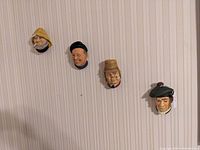All four Bossons wall figurines mounted on wallpaper showing the fisherman, man with pipe, man with cigar, and Scottish golfer.