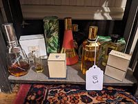Front view of assorted vintage ladies' fragrance bottles and boxes arranged on a shelf, with visible brand names and various shapes, colors, and packaging styles.