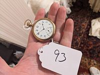 Front view in hand showing white enamel dial, Arabic numerals and sub-seconds