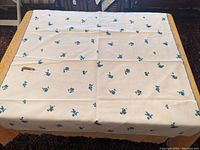 Full view of the white linen tablecloth spread out on a table, showing the overall pattern and condition.