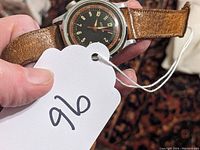 Full view of Mentor wristwatch with brown leather strap held in hand showing overall condition and dial face.