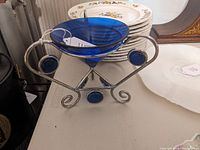 Side view of cobalt blue glass bowl set in chromed metal frame with decorative accents