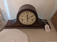 Full image of the Seth Thomas mantle clock showing the clock face, wood casing, and original key on the right side