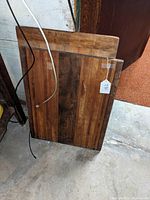 Photo of the wooden boards leaning against a wall, showing front of multi-colored cutting board and front of bread board