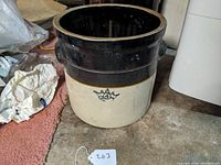 Front view of the stoneware crock showing the Ransbottom logo on the white lower part with the brown glaze above.