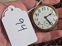 Front view of watch dial and case held in hand with tag visible.