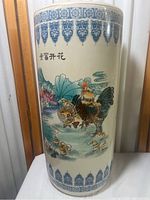 Front view of the tall cylindrical porcelain vase showing rooster and chicks with blue patterned borders and calligraphy.