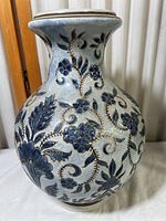 Close-up front view of blue and white floral decorated Asian ceramic vase showing detailed flower and leaf patterns on crackled glaze.