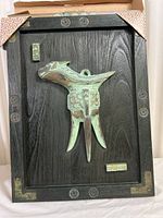 Full view of bronze cattle cup mounted on wood plaque with decorative metal corner accents.